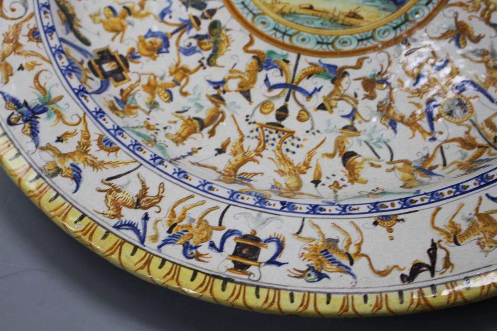 A 19th century Italian 17th century style maiolica charger, decorated with cherubs flanking a cartouche within bands of stylised beasts